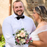 Froehliches Brautpaar mit Blumenstrauss