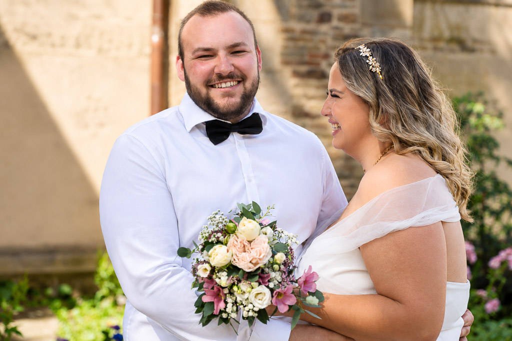 Froehliches Brautpaar mit Blumenstrauss